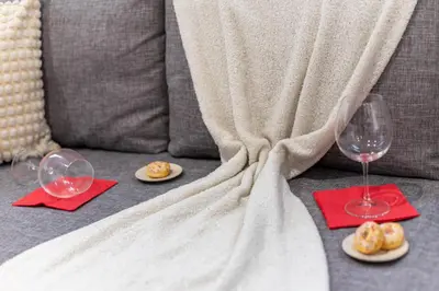 two wine glasses and plates of food on a couch at Lavie Maison Sauna and Hot Tub Seaside in Nice