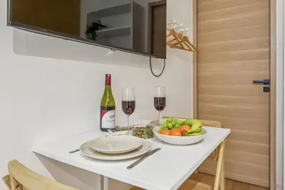 a white table with a bowl of fruit and wine glasses at Lavie Maison Hot Tub Seaside Studio in Nice