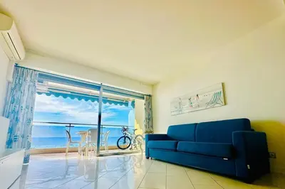 a living room with a blue couch and a view of the ocean at Art de vivre sur la Promenade in Nice