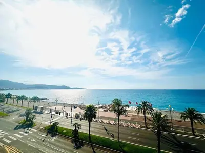 a view of a beach with palm trees and the ocean at Art de vivre sur la Promenade in Nice
