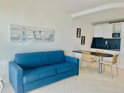 a living room with a blue couch and a table at Art de vivre sur la Promenade in Nice