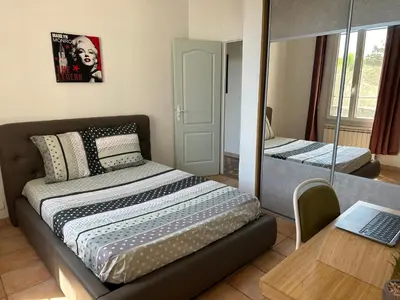 a bedroom with a bed and a desk with a laptop at Maison de ville à Nice Ouest dans propriété arborée in Nice