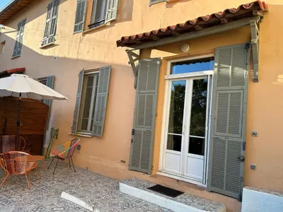 a building with a door and a table with an umbrella at Maison de ville à Nice Ouest dans propriété arborée in Nice