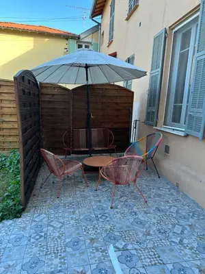 a table and chairs under an umbrella on a patio at Maison de ville à Nice Ouest dans propriété arborée in Nice