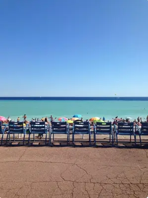 a group of people sitting on a beach with umbrellas at Superbe appartement de 3p pieces dans residence avec piscine et climatisation in Nice