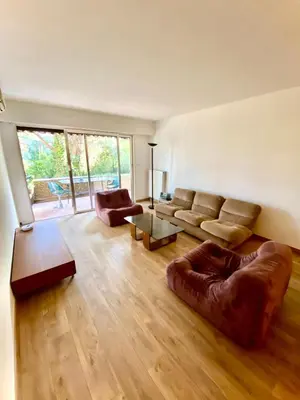 a living room with a couch and a table at Superbe appartement de 3p pieces dans residence avec piscine et climatisation in Nice