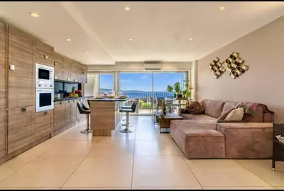 a living room with a couch and a table and a kitchen at Magnificent 3 Rooms-Sea View-Terrace-Pool in Nice