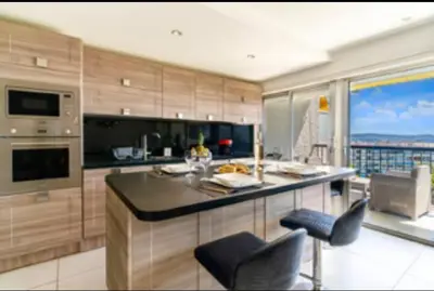 a kitchen with a counter and some chairs in it at Magnificent 3 Rooms-Sea View-Terrace-Pool in Nice