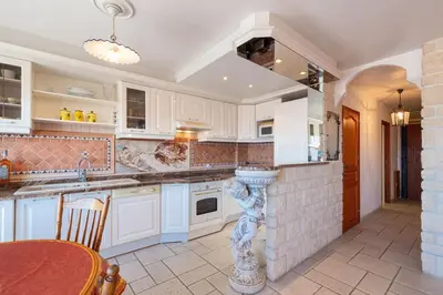 a kitchen with white cabinets and a table at 2 PIECEs BALCON VUE IMPRENABLE MER---VILLE---MONTAGNE in Nice