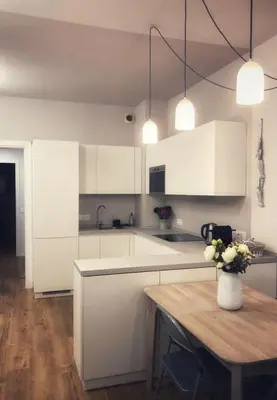 a kitchen with white cabinets and a table with a vase of flowers at Suite Offenbach FSHH in Nice