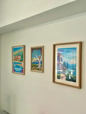 three framed posters on a white wall at Appartement exception les pieds dans l'eau in Èze
