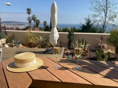a hat and two glasses of wine on a wooden table at Unique appartement à Nice vue mer imprenable in Nice