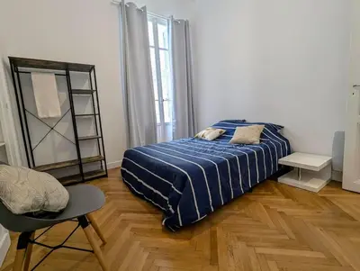 a bedroom with a bed and a chair and a mirror at 3 Pièces 70m2 Coeur de Nice in Nice