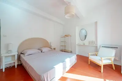 a white bedroom with a bed and a chair at Charmant Appartement 2P au Cœur du Vieux Nice in Nice