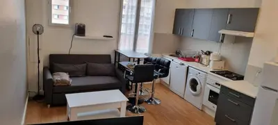 a living room with a couch and a kitchen at Appartement lumineux in Nice
