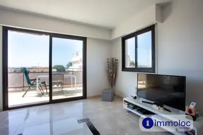 a living room with a large flat screen tv and windows at Air-conditioned apartment with park and swimming pool à Cagnes in Cagnes-sur-Mer
