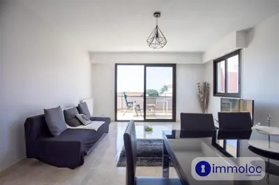 a living room with a couch and a table at Air-conditioned apartment with park and swimming pool à Cagnes in Cagnes-sur-Mer