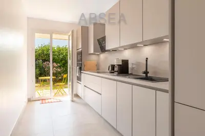 a kitchen with white cabinets and a view of a yard at Nice Absea Fabron 2 in Nice