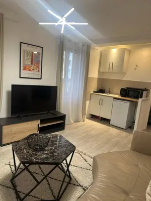 a living room with a flat screen tv and a table at Carras in Nice