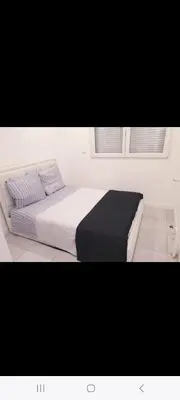 a bed in a white room with two pillows at Grand Appartement, 2 ou 3 ou 4 pieces, tramway sur place, proche gare sncf St Augustin 5 min, aéroport à 7 min, plage ou Allianz riviera 10 min, palais nikaia 2 min , supermarché sur place, parking possible si disponible ou payant à 1000 metre in Nice