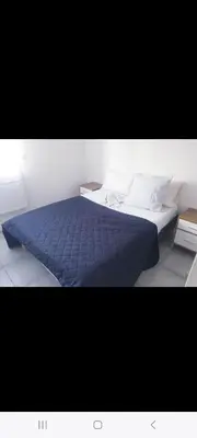 a bed with a blue comforter and pillows in a room at Grand Appartement, 2 ou 3 ou 4 pieces, tramway sur place, proche gare sncf St Augustin 5 min, aéroport à 7 min, plage ou Allianz riviera 10 min, palais nikaia 2 min , supermarché sur place, parking possible si disponible ou payant à 1000 metre in Nice