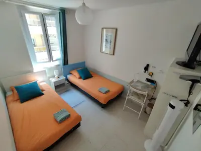 a small room with two beds and a table at Private Room in Shared Apartment in the Center of Nice in Nice