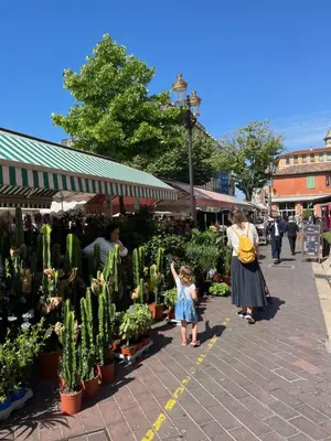 a woman and a little girl looking at plants in a market at Le Bosio-studio avec vue mer in Nice
