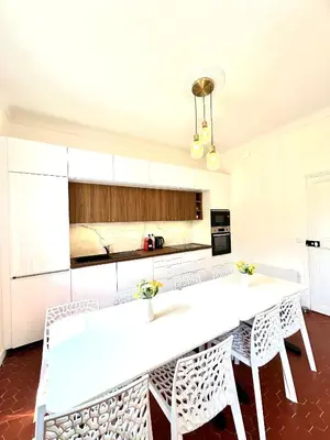 a kitchen with white cabinets and white tables and chairs at Villa Lila in Nice