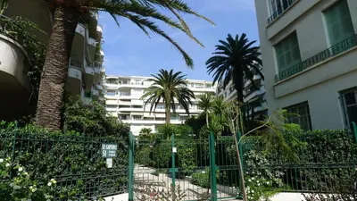 a fence in front of a building with palm trees at LE CAPITOL 2 AP4421 By Riviera Holiday Homes in Nice
