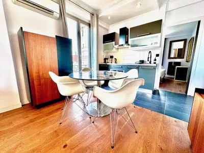 a kitchen with a table and white chairs in a room at ApartHotel Riviera - LE PETIT BALCON DE L'OPERA - Old Town Promenade des Anglais in Nice
