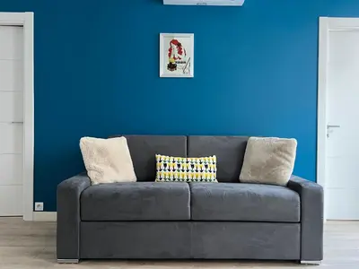 a black couch in a room with a blue wall at Center 2 min walk to beach quiet sunny balcony in Nice