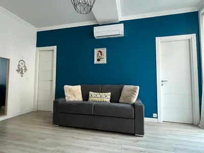 a couch in a living room with a blue wall at Center 2 min walk to beach quiet sunny balcony in Nice