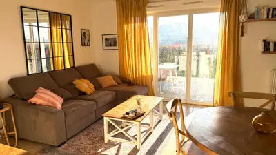 a living room with a couch and a large window at Superbe appartement lumineux en rez de jardin in Saint-Laurent-du-Var