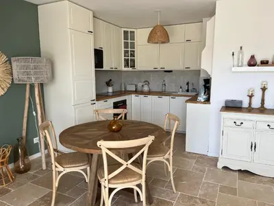 a kitchen with a wooden table and chairs at Superbe appartement lumineux en rez de jardin in Saint-Laurent-du-Var