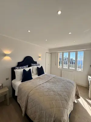 a bedroom with a large bed and windows at Mala Beach Sea View in Cap d'Ail
