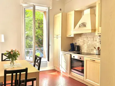 a kitchen with white cabinets and a table and a window at 2P Moderne Riquier proche Port, Gare, Tramway in Nice