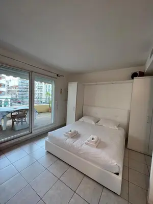 a white bed in a room with a large window at La Terrasse de Palais des Arts in Nice