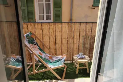 a patio with a rocking chair and a table at Appartement de charme centre vieux village in Villefranche-sur-Mer