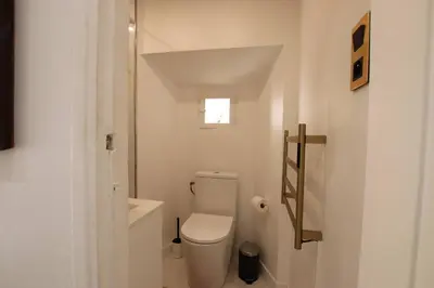 a white bathroom with a toilet and a window at Appartement de charme centre vieux village in Villefranche-sur-Mer