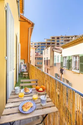 a table with plates of food on a balcony at Appartement de charme centre vieux village in Villefranche-sur-Mer