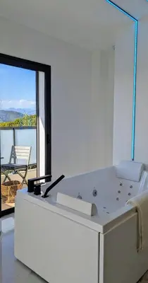 a white bath tub in a room with a large window at Olive Grove Retreat in La Trinité