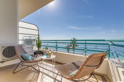 a balcony with chairs and a table and the ocean at LE 3 PROMENADE AP4424 By Riviera Holiday Homes in Nice
