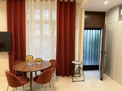a dining room with a table and chairs and red curtains at Extraordinaire grand studio au centre 6 minutes à pied de la plage et l'hôtel Negresco in Nice