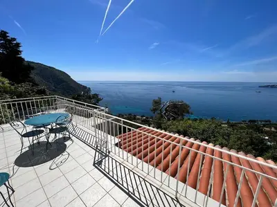 a balcony with a table and chairs and the ocean at Entre les citronniers et la mer in Èze