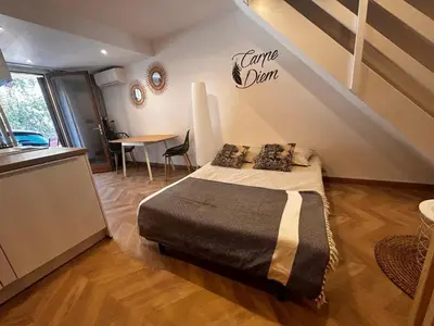 a bedroom with a bed and a table and a staircase at Studio moderne climatisé avec coin nuit, proche mer et Hauts de Cagnes in Cagnes-sur-Mer