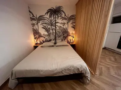 a bedroom with a bed with palm trees on the wall at Studio moderne climatisé avec coin nuit, proche mer et Hauts de Cagnes in Cagnes-sur-Mer