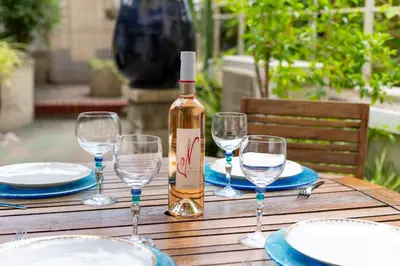 a bottle of wine sitting on a wooden table with glasses at Happyfew La Promenade 53 in Nice