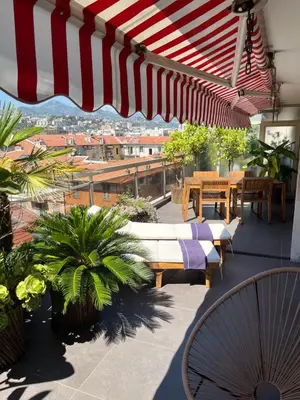 a patio with tables and chairs and an umbrella at Splendide penthouse au coeur de Nice in Nice