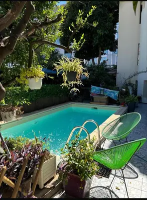 a swimming pool with a green chair and some plants at Villa CALIFORNIA in Nice