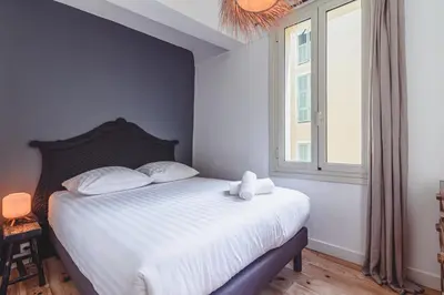 a bedroom with a bed with white sheets and a window at Bohème-Chic au cœur du VIEUX NICE #Lovely in Nice
